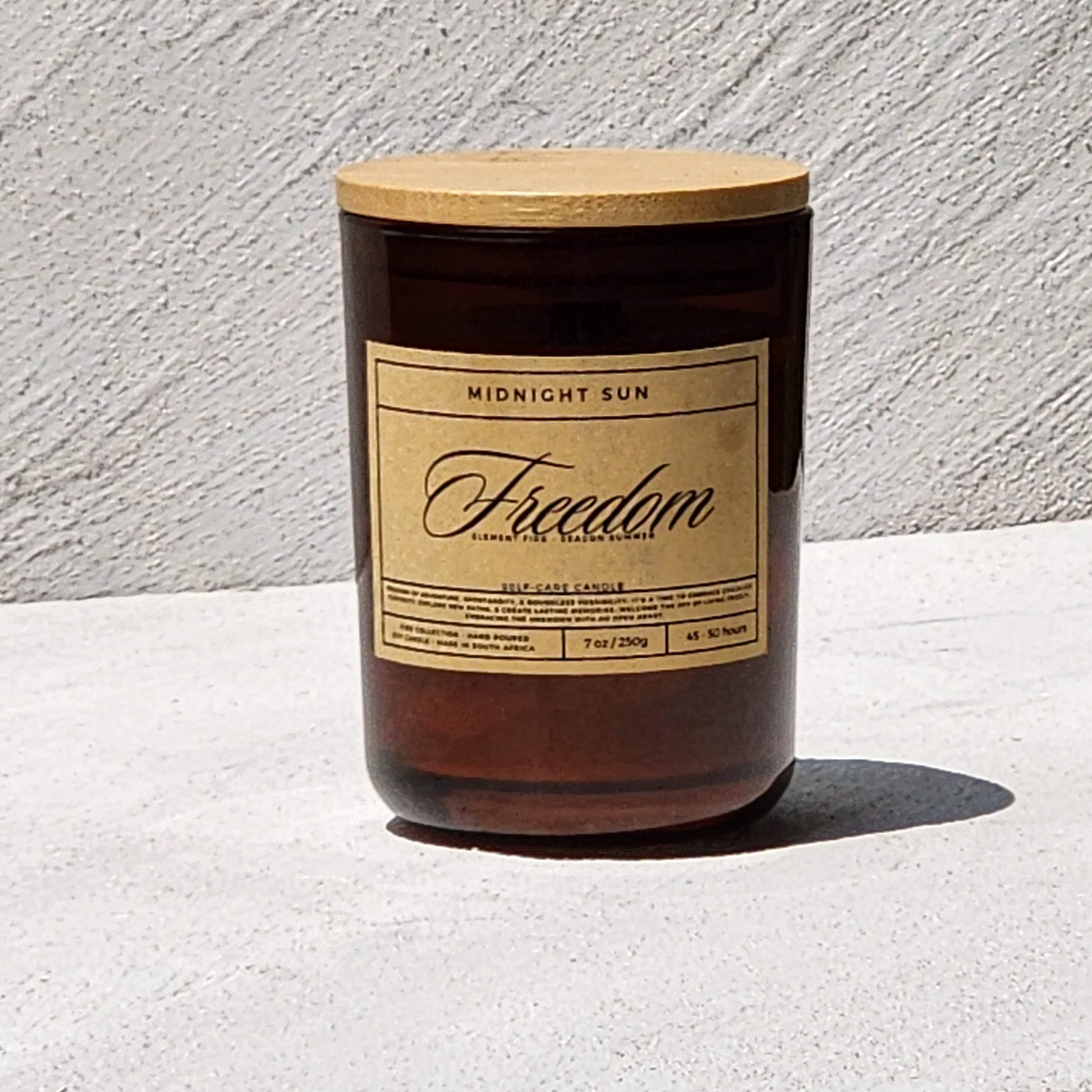 Candle with a wooden lid and 'Freedom' label on a light surface.